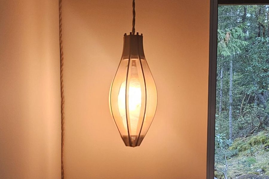 A ribbed wooden lantern lit and hanging by a window
